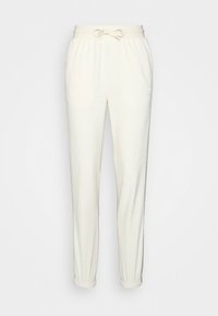 Pantaloni tuta di colore crema; realizzati in un morbido tessuto con vita elastica e cordino, caratterizzati da polsini a coste alle caviglie.