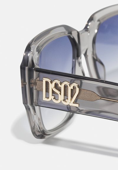Ochelari de soare gri transparenti cu lentile degradate albastre. Au un logo auriu "DSQ2" pe bradă și un design elegant, unghiular al ramei.
