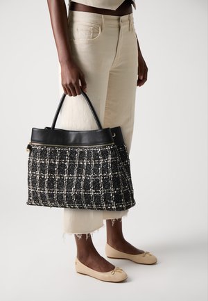 Borsa tote in tweed bianco e nero con superficie testurizzata, dettagli in pelle, chiusura con zip e manici arrotondati.