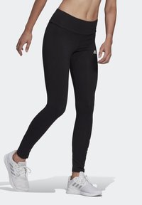 Svarta träningsleggings med en bred, hög midja, slät yta, smal passform och vitt logotypaccent på vänster sida.