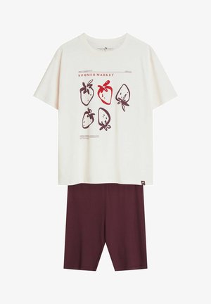 Biała koszulka z krótkim rękawem z czerwonymi i brązowymi szkicami truskawek oraz napisem "Summer Market", w połączeniu z jednolitymi ciemnoczerwonymi spodenkami do kolan.