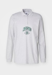 Ljusgrå långärmad polo med kvartdragkedja och grön broderad Adidas-logga på bröstet. Mjuk bomullsstruktur, avslappnad design.