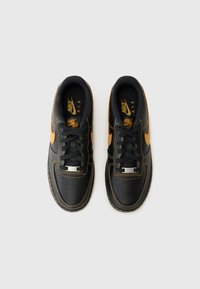 Mustad must nahk Nike Air Force sneakerid oranžide aktsentidega, sellel on perforatsioonid, mustad paelad ja metallist detailid keelel.