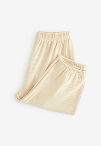 Pantaloni beige a coste con vita elastica, caratterizzati da una morbida texture e una vestibilità morbida, piegati ordinatamente su uno sfondo bianco.