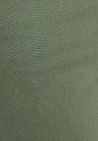 Groene stof met een gladde textuur en een diagonaal weefpatroon, die een zachte glans vertoont en een uniforme kleur heeft.