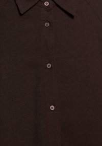 Ciemnobrązowa koszula zapinana na guziki z czterema widocznymi okrągłymi guzikami i ostrym kołnierzem, pokazująca drobną fakturę materiału.