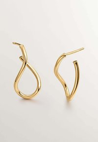Pendientes de aro en tono dorado con un diseño retorcido y fluido. Presenta una textura suave y una silueta esbelta. Cada pendiente cuenta con un cierre de tipo post.
