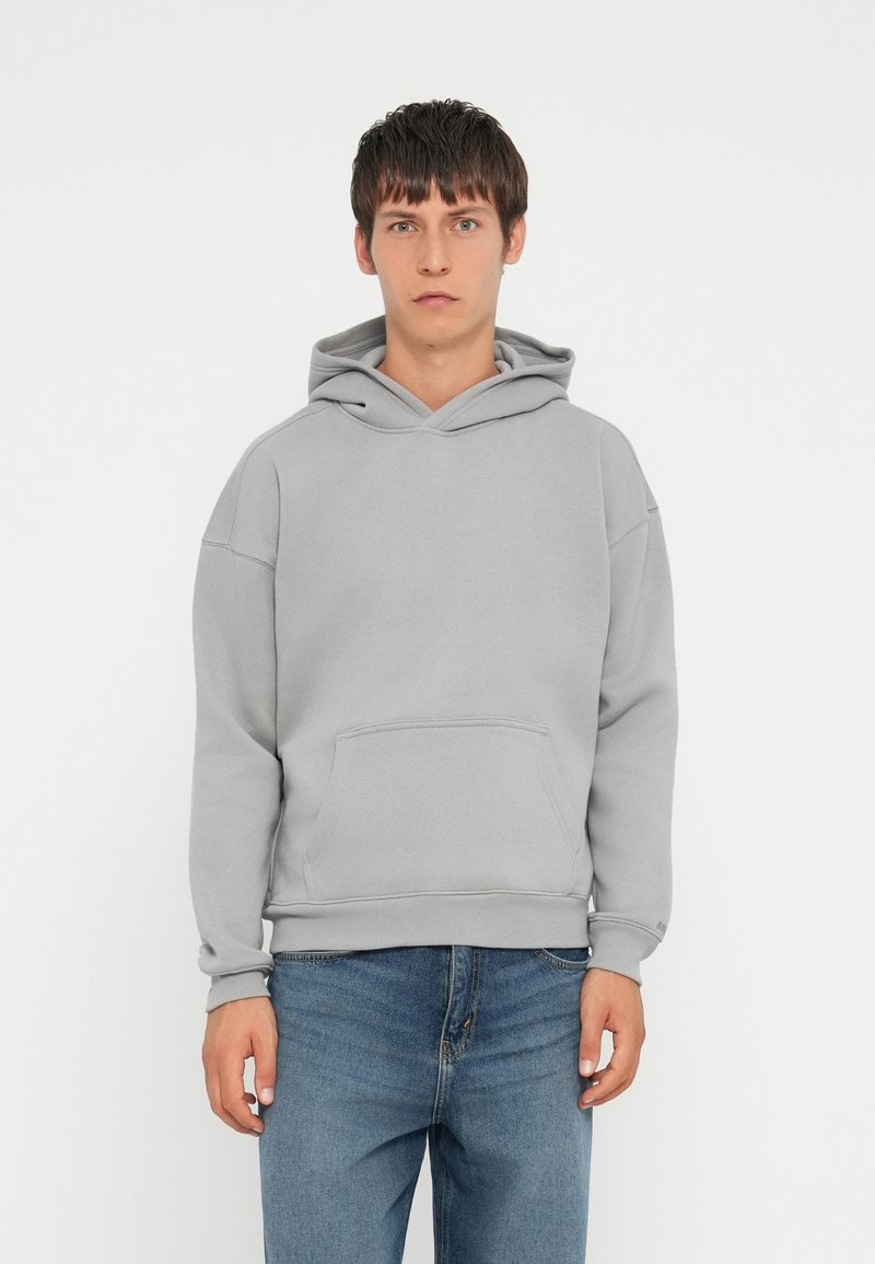 Lys grå hoodie med en kænguru-lomme, ribbede manchetter og en afslappet pasform. Fremstillet af blødt stof med en glat tekstur og justerbar snorhætte.