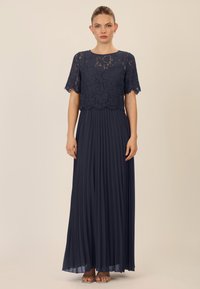 Marineblaue Kleid mit einem Spitzenoberteil und kurzen Ärmeln sowie einem plissierten Rock. Der Stoff hat eine glatte Textur und ein fließendes Design.