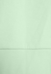 Tissu vert clair avec une surface texturée et une finition lisse et sans coutures. Le matériau est tricoté et présente une couleur simple et uniforme.