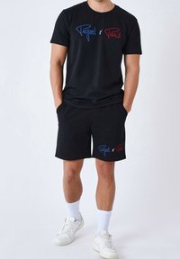 Ensemble de T-shirt noir et de shorts avec le texte brodé "Project" en bleu et "Paris" en rouge. Matière en mélange de coton, coupe décontractée, associé à des baskets blanches.