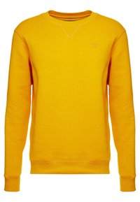 Sudadera amarilla hecha de una tela suave, con cuello redondo, mangas largas y puños acanalados. Pequeño detalle de logo en la parte frontal.