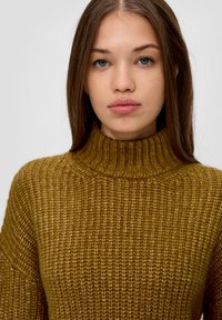Senfgelbfarbener Rollkragenpullover im dicken Strickdesign mit gerippter Textur und eng anliegendem Halsausschnitt, der einen subtilen Glanz aufweist.