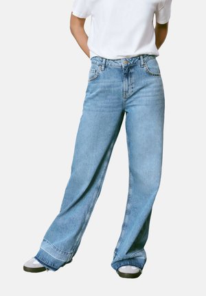 Jeans de mezclilla de pierna ancha color azul claro, con una cintura alta, bolsillos delanteros y detalles de dobladillo deshilachado. Combinados con zapatillas grises y blancas.