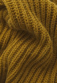 Tejido de punto en un rico color amarillo mostaza, que presenta un patrón de ribete texturizado y fibras suaves y esponjosas.