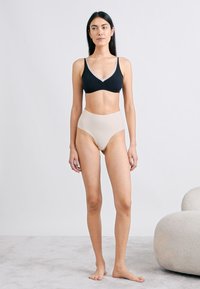 Μαύρο σουτιέν με γκρι ανοιχτό περίγραμμα συνδυασμένο με εσώρουχα υψηλής μέσης σε γυμνή απόχρωση. Λείο ύφασμα, σχεδιασμός χωρίς ραφές και ουδέτερα χρώματα.