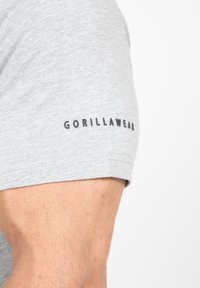 Grijze katoenen t-shirt met een getailleerd ontwerp, korte mouwen en een zwart "GORILLAWEAR" logo op de linkermouw.