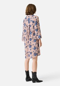 Rochie florală cu mâneci trei sferturi, din stofă roz cu modele florale albastre. Purtați-o cu cizme negre până la gleznă, cu tăietură până la genunchi, textură moale.