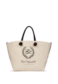 Beige canvas draagtas met zwarte bies en handvatten. Voorzien van een zwart logo en laurierontwerp dat op de voorkant is gedrukt. Groot, open formaat.