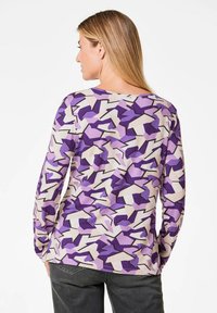 Langarmshirt in lila, lavendel und cremefarbenem geometrischem Muster. Glattes Material mit lockerer Passform und rundem Ausschnitt.