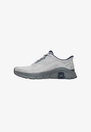 Zapatilla deportiva gris claro y azul marino con parte superior de malla transpirable, suela acolchada y diseño sin cordones, mostrada desde el lado exterior.