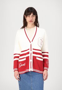 Rød og hvit cardigan med V-hals, knappelukking, stripete design, lommer og broderte logo-detaljer. Laget av mykt strikkemateriale.