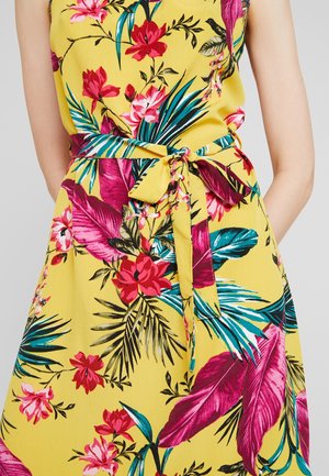 Abito floreale giallo con motivi tropicali in rosa, verde e blu. Include una cintura annodata in vita e una texture di tessuto liscia.