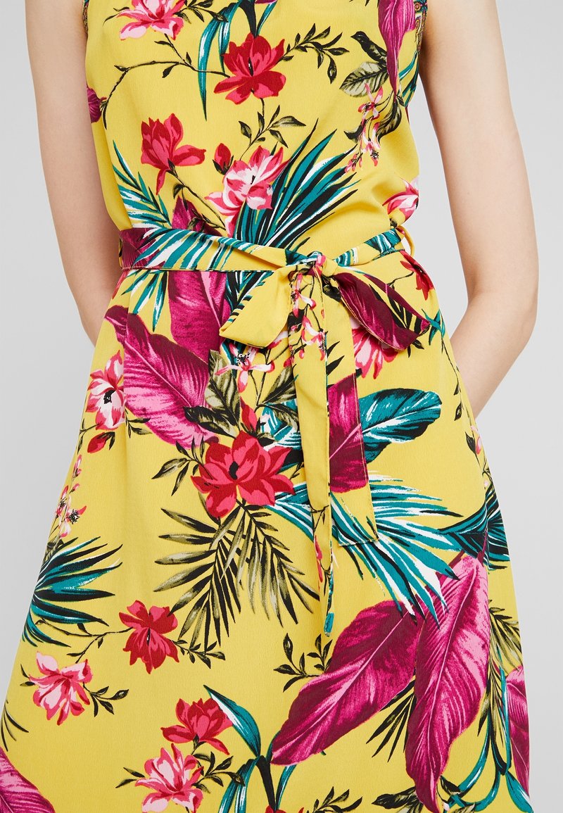 Yellow floral dress featuring tropical patterns in pink, green, and blue. Includes a tied waistbelt and smooth fabric texture.