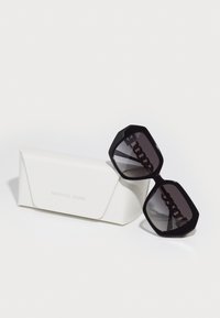 Ochelari de soare supradimensionați, negri, cu ramă geometrică, lentile întunecate și accente din lanț. Vine cu un etui alb cu inscriptionarea "MICHAEL KORS."