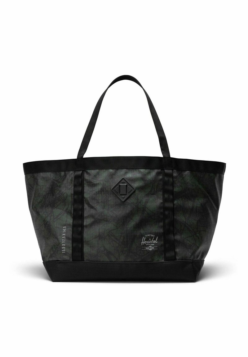 Sac fourre-tout Herschel à motif camouflage noir et vert foncé, avec deux poignées, patch logo et dimensions imprimées sur le côté.