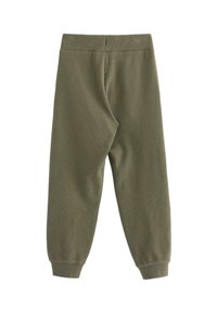 Pantaloni ribbed verde oliva con vestibilità affusolata. Presentano una cintura elastica e caviglie cuffate. Tessuto morbido, progettato per il comfort.