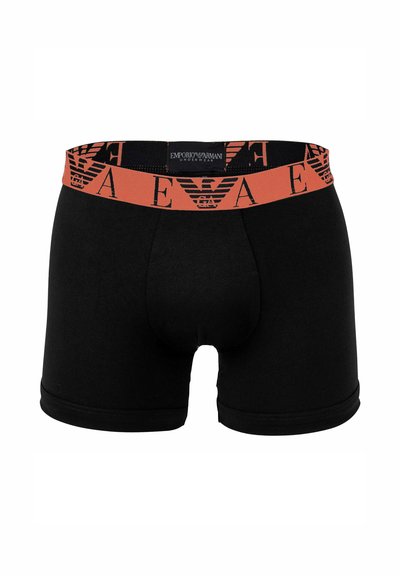 Schwarze Boxershorts aus Baumwolle mit einem orangefarbenen elastischen Bund, der ein sich wiederholendes Logo-Muster trägt, und einem enganliegenden Design.