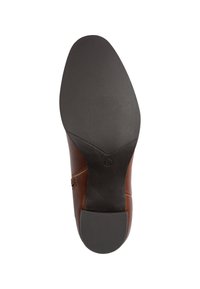 Semelle en cuir marron pour bottes avec une semelle extérieure en caoutchouc noir texturé, présentant une forme effilée lisse et des détails de couture subtils le long du côté.