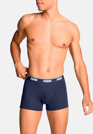 Marineblaue Boxershorts mit einem weißen PUMA-Logo auf dem elastischen Taillenbund. Hergestellt aus einem glatten, dehnbaren Stoff mit einem enganliegenden Design.