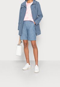 Chaqueta ligera azul, camiseta de tie-dye rosa, pantalones cortos de mezclilla, zapatillas blancas y un bolso blanco. Texturas suaves, diseño casual.