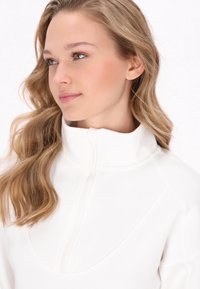 Felpa bianca con zip, colletto alto, texture liscia e design del corpo triangolare. Presenta una zip centrale e cuciture alla moda.