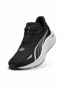 Une chaussure de sport noire avec une tige texturée, une semelle blanche et un design épuré. Elle présente des lacets et de subtils accents gris sur le côté.