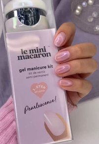 Kit de manucure en gel dans une boîte transparente avec des composants blancs et argentés, portant une étiquette rose indiquant "Pearlescence!" et les détails du produit.