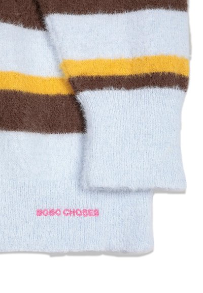 Manche et ourlet de pull en maille douce avec des rayures blanches, marron et jaunes et un texte rose "BOBO CHOSES" brodé sur l'ourlet.
