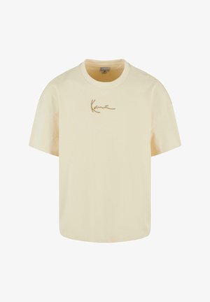 Tricou cu mânecă scurtă, de culoare crem, din bumbac. Prezintă un logo maro distinctiv pe față, decolteu rotund și o croială lejeră.