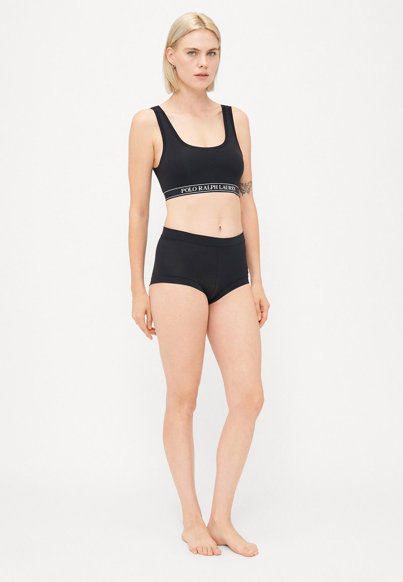 Sort sports-bh og matchende højtaljede boyshorts med en logo-bånd, glat tekstur og tætsiddende design. Ingen synlige mønstre eller accenter.