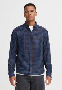 Langarm overhemd in bruin met een blauw geruit patroon. Beschikt over een kraag en een rechte zoom. Casual pasvorm.