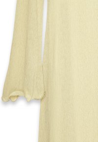 Pitkä beige mekko, jossa on hillitty rypytys ja skaalatut, röyhelömuotoiset hihansuut valkoista taustaa vasten.