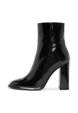 Bottine noire en cuir verni brillant, avec un bout pointu et un large talon haut. Sans quincaillerie visible ni motifs.
