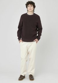 Pull en rib à côtes marron, pantalon crème et chaussures marron. Encolure ras du cou simple et coupe décontractée avec un tissu texturé. Tenue décontractée.