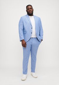 Lys blu linen dress med jakke med notched lapel og matchende bukser, parret med en hvit t-skjorte og hvite joggesko.