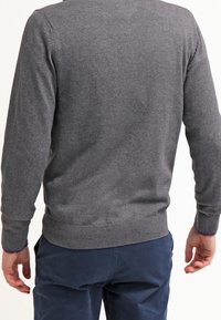 Grauer Strickpullover mit rundem Halsausschnitt und gerippten Bündchen an Ärmeln und Saum. Der Stoff ist weich, hat eine glatte Textur und keine sichtbaren Muster.