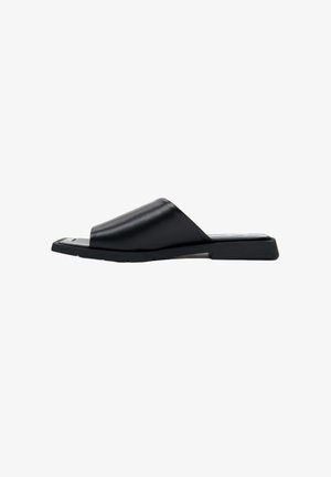 Zwarte leren slip-on sandaal met een brede bovenband, platte zool en minimalistisch ontwerp. Soepele textuur met een licht gebogen vorm.
