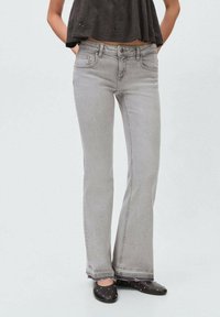 Grå utsvängda jeans med en deniminspirerad textur, med fransade fållar och fem fickor. Bärs med en svart topp och svarta flat shoes med nitar.