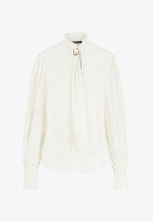 Blouse blanche à manches longues avec col montant, détail œillet doré, poignets froncés et un lien lâche suspendu au col.